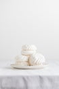 White airy zephyr or marshmallow shells on a plate on a white table, with space for text