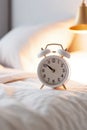 white alarm clock on bedside table in bedroom, woman sleeping on bed in background. AI Generated