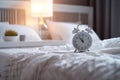 white alarm clock on bedside table in bedroom, woman sleeping on bed in background. AI Generated Royalty Free Stock Photo