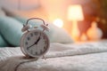 white alarm clock on bedside table in bedroom, woman sleeping on bed in background. AI Generated Royalty Free Stock Photo