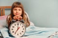 White alarm clock in the hands of a happy smile child girl in the bedroom. 7 o& x27;clock in the morning. Copy space Royalty Free Stock Photo