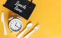 White Alarm clock with knife fork and spoon for mealtime or diet concept on yellow background, free space for text. Royalty Free Stock Photo