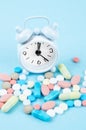 The white alarm clock and many drug on a blue background. Taking medicine at the right time concepts