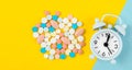 The white alarm clock and many drug on a yellow background. Taking medicine at the right time concepts