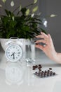 White alarm clock and medical pills with a glass of water on the table. Healthcare and medicine. Vitamins and mineral supplements Royalty Free Stock Photo