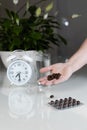 White alarm clock and medical pills with a glass of water on the table. Healthcare and medicine. Vitamins and mineral supplements Royalty Free Stock Photo