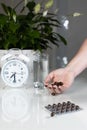 White alarm clock and medical pills with a glass of water on the table. Healthcare and medicine. Vitamins and mineral supplements Royalty Free Stock Photo