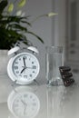 White alarm clock and medical pills with a glass of water on the table. Healthcare and medicine. Vitamins and mineral supplements Royalty Free Stock Photo