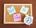 White alarm clock, notes on a cork Board with the concept of back to school. Brown background. Flat layer Royalty Free Stock Photo