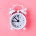 White alarm clock on a pastel blue, pink background. Royalty Free Stock Photo