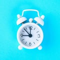 White alarm clock on a pastel blue, pink background. Royalty Free Stock Photo