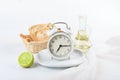 White alarm clock on a white plate against the background of a bottle of oil, bread and lime. Royalty Free Stock Photo