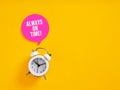 White alarm clock ringing with always on time message on yellow background Royalty Free Stock Photo