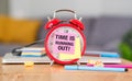 White alarm clock with Time is Running Out text on lithe background, concept with books. Royalty Free Stock Photo