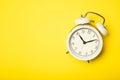 White alarm clock on a yellow background. Top view, place for text Royalty Free Stock Photo