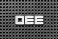 White letter in word OEE abbreviation of overall equipment effectiveness on black pegboard background