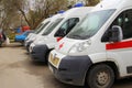 White ambulance with a red stripe with blue flashing lights on a city street in Russia