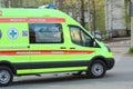 White ambulance with a red stripe with blue flashing lights on a city street in Russia