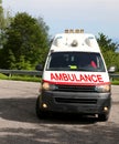 White ambulance van with text speeding fast with blue lights flashing Royalty Free Stock Photo
