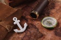 Anchor near leather copy book, compass and telescope on old world map