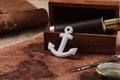 Anchor near open wooden box with telescope on world map