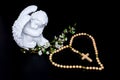White angels statue with white flowers on black background and wooden rosary Royalty Free Stock Photo
