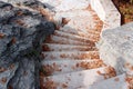 White angled stone staircase among rocks with dry autumn leaves