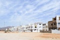 Arabian rectangular and square downtowns, houses in the desert with windows against the background of yellow sand and beautiful bl Royalty Free Stock Photo