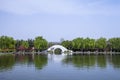 A white arch bridge is especially beautiful against the background of willows and green peaches