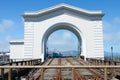 White arch structure on a pier with dual railway tracks, marked by a \