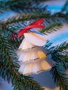 White aromatic candle in the shape of a decorative Christmas tree on a fir branch