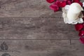 White aromatic vanilla candle and red rose petals. Wooden background. Aromatherapy concept. Romantic background. Rose frame