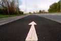 White arrow on a black asphalt surface in focus. Direction sign on a road Royalty Free Stock Photo