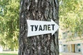 The white arrow indicates the direction to the right attached to the tree, inscription restroom in Russian