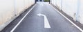 White arrow traffic sign indicates minor road to turn left to major road and white footpath lines on the asphalt rural road in