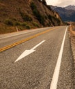 White arrow traffic sign, yellow dividing lines and white footpath line on the asphalt rural road Royalty Free Stock Photo