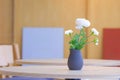 White artificial flowers in black terracotta vase on wooden round dining table inside of modern coffee shop Royalty Free Stock Photo