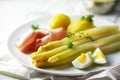 White asparagus dish with potatoes, ham and egg on a white plate