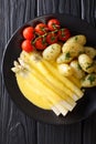 White asparagus with hollandaise sauce and new potatoes close-up on a plate. vertical top view Royalty Free Stock Photo