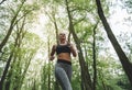 White athletic girl in sportswear running in the Park among the trees, runner