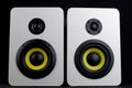 White audio speakers on a black background. Minimalistic audio speakers with yellow subwoofer