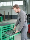 The auto mechanic takes the tool from the tool box. Indoors . Royalty Free Stock Photo