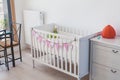 Baby bed crib in child room interior, decorated with paper handmade garland