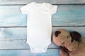 White baby bodysuit mockup with toy on wooden background. Styled stock photography. Mock up