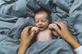 White baby boy sleeping in soft blue bed sheets and hands of his mom adjusting him. Mother putting baby to sleep Royalty Free Stock Photo