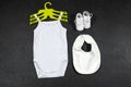 White baby girl or boy bodysuit mockup flat lay with bib and shoes on grunge gray concrete background. Design onesie template Royalty Free Stock Photo