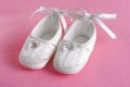 White baby's bootees or shoes on pink sheet
