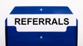 On a white background, a blue folder for papers. In the folder is a sheet of paper with the word REFERRALS