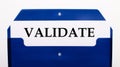 On a white background, a blue folder for papers. In the folder is a sheet of paper with the word VALIDATE Royalty Free Stock Photo