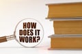 On a white background, books and a magnifying glass, inside which it is written - HOW DOES IT WORK Royalty Free Stock Photo